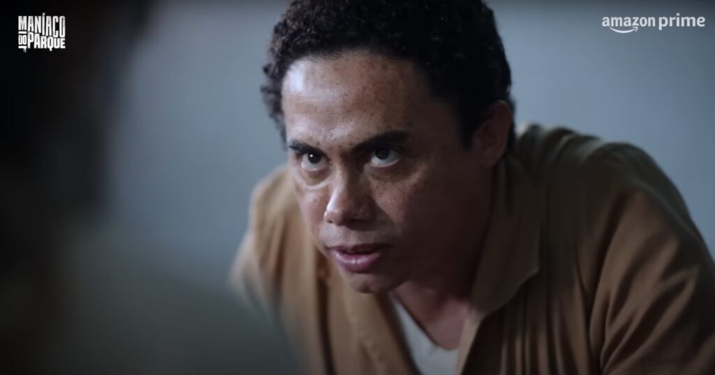 Filmes de suspense psicológico: Homem de uniforme bege encara alguém com um olhar intenso em uma sala fria.