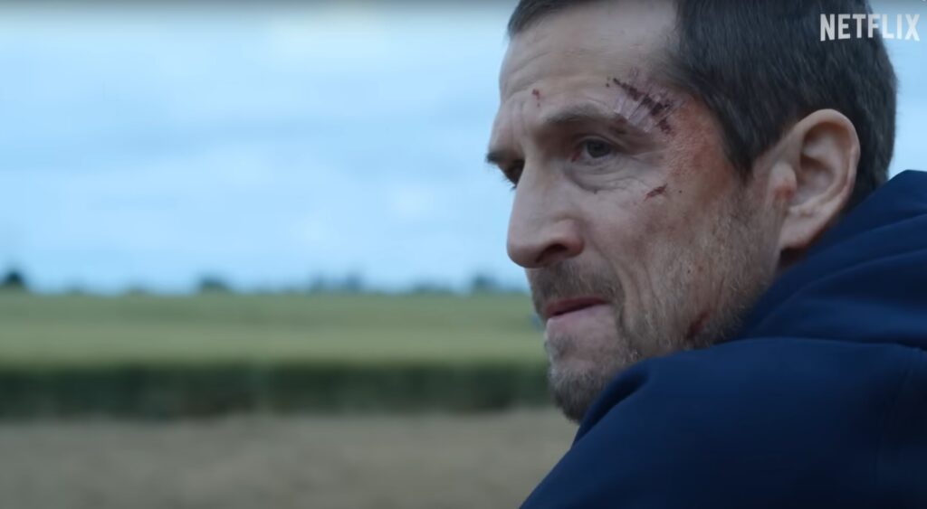 Confira os 5 Melhores Filmes de Ação para Assistir na Netflix em 2025 23 Homem ferido encara o horizonte em cena dramática de um dos melhores filmes de ação da Netflix.