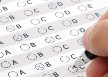 Pessoa preenchendo cartão-resposta de concurso público. Representando "como passar em um concurso público?"