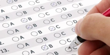 Pessoa preenchendo cartão-resposta de concurso público. Representando "como passar em um concurso público?"