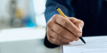 Homem preenchendo prova de concurso público. Falando sobre concursos públicos 2025.