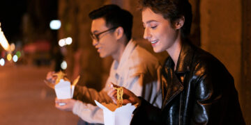 Do Rock à Ópera: Quais os Hábitos Culturais da Classe Alta Mais Jovem? 5 Dois jovens apreciando comida de rua à noite, refletindo hábitos culturais da classe alta.