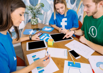 Equipe analisando dados e dispositivos, discutindo estratégias com prompts para criar conteúdos.