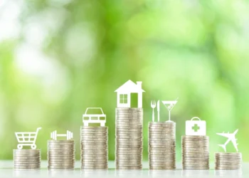 Pilhas de moedas em sequência. Cada uma delas possui um símbolo sobre si (casa, carro, carrinho de compras etc). Analisando quanto custa viver bem no Brasil.