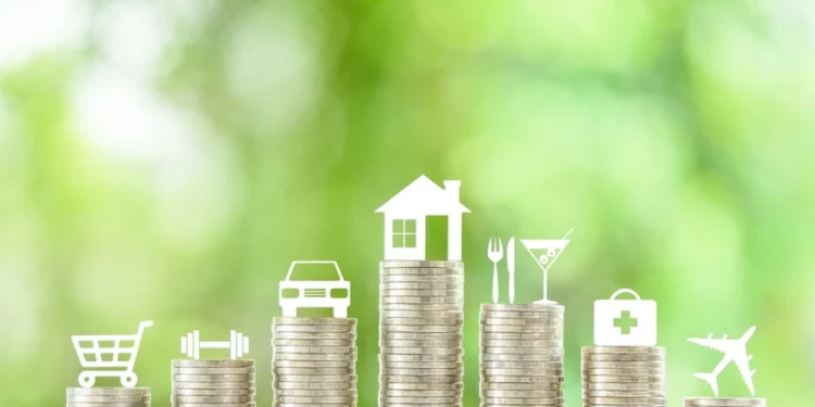 Pilhas de moedas em sequência. Cada uma delas possui um símbolo sobre si (casa, carro, carrinho de compras etc). Analisando quanto custa viver bem no Brasil.