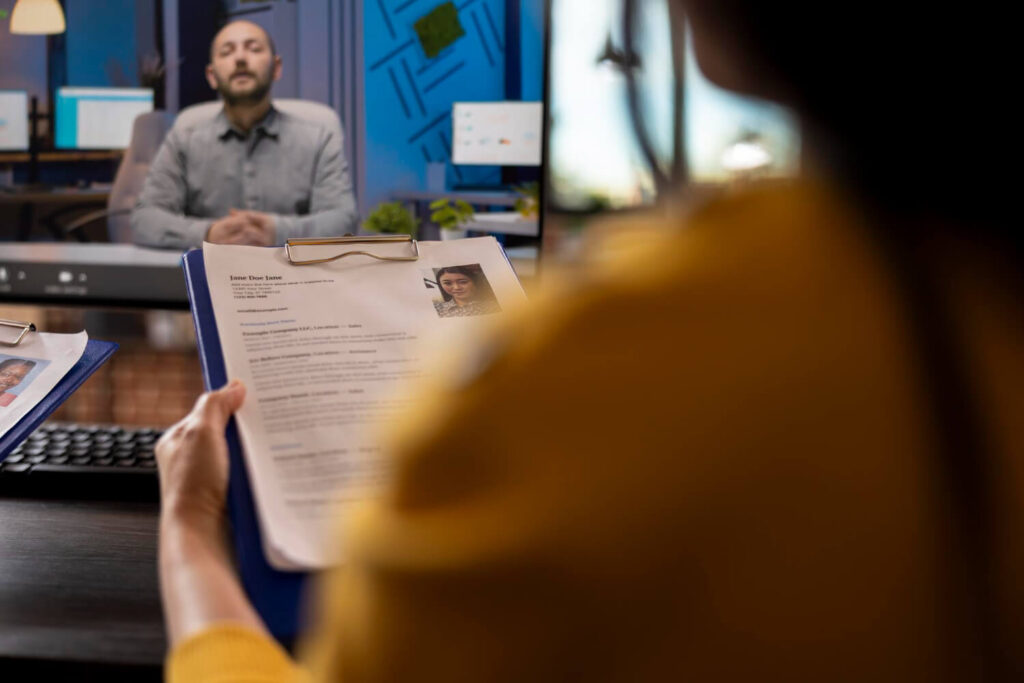 Vagas Temporárias: Como Garantir uma Renda Extra em 2025? 1 Candidata apresenta currículo a recrutador em entrevista para vagas temporárias.
